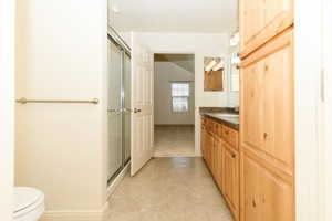 Full bath featuring vanity, a shower stall, toilet, and tile patterned floors