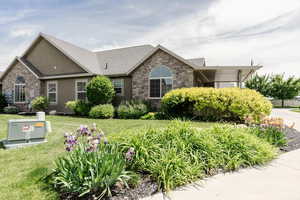 Ranch-style house with stone siding, a front lawn, and stucco siding