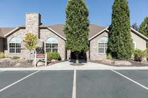 View of front of property featuring stone siding, a chimney, and roof with shingles