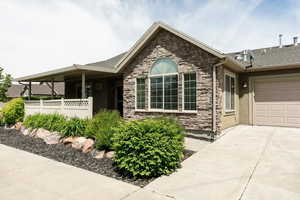 Ranch-style house featuring concrete driveway, stone siding, a garage, and stucco siding