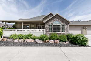 Ranch-style house with stone siding, concrete driveway, an attached garage, and stucco siding