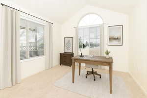 Office space featuring light colored carpet and lofted ceiling