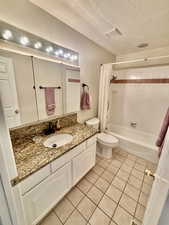 Full bath featuring tile patterned floors, toilet, visible vents, shower / bathtub combination with curtain, and vanity