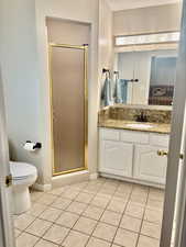 Full bath with tile patterned floors, toilet, vanity, baseboards, and a stall shower