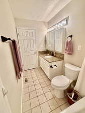 Bathroom featuring a textured ceiling, vanity, toilet, tile patterned flooring, and visible vents