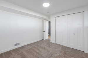 Unfurnished bedroom with light colored carpet and a closet