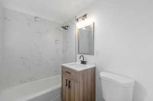 Full bathroom with vanity, tiled shower / bath combo, and toilet