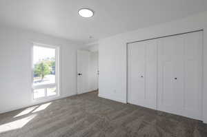 Unfurnished bedroom with a closet and dark colored carpet