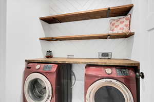 Laundry area featuring washing machine and dryer and decor wall