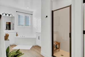 Bathroom featuring vanity, shower with separate bathtub, and wood-style floors