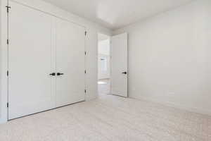 Unfurnished bedroom featuring light carpet and a closet