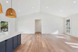 Unfurnished living room with lofted ceiling and light wood-type flooring