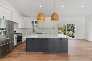 Kitchen with white cabinets, a healthy amount of sunlight, and high end appliances