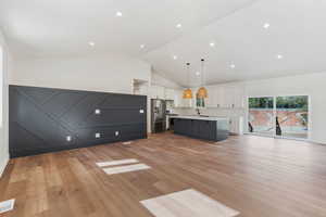 Kitchen featuring a kitchen island, white cabinetry, pendant lighting, light hardwood / wood-style floors, and stainless steel appliances