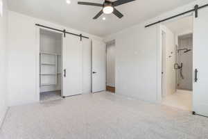 Unfurnished bedroom featuring a closet, ceiling fan, ensuite bathroom, and a walk in closet