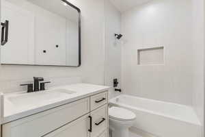 Full bathroom featuring vanity, tiled shower / bath combo, and toilet