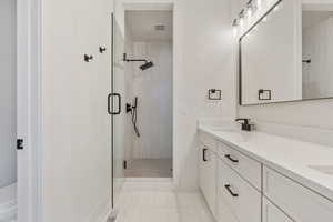 Bathroom featuring vanity, toilet, and an enclosed shower