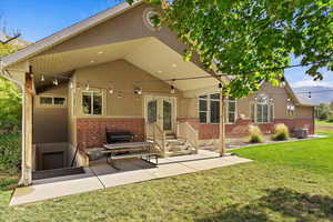 Rear view of house with a patio area, cooling unit, and a yard