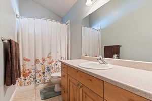 Full bathroom with lofted ceiling, toilet, tile patterned flooring, shower / bath combination with curtain, and vanity