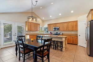 Tiled dining room featuring a chandelier, french doors, high vaulted ceiling, and plenty of natural light