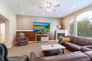 Carpeted living room with ceiling fan and wood walls