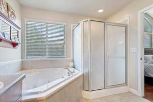 Bathroom featuring vanity, shower with separate bathtub, and tile patterned flooring