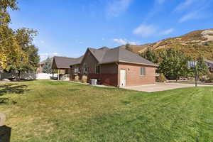 View of property exterior featuring a mountain view, central AC, and a lawn