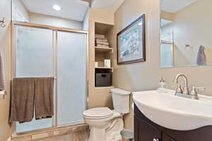 Bathroom with toilet, a shower with shower door, and vanity