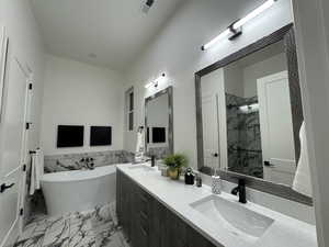 Bathroom featuring vanity and separate shower and tub