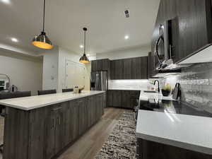 Kitchen with stainless steel appliances, a kitchen island, sink, and decorative light fixtures