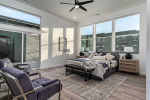 Bedroom with ceiling fan, light hardwood / wood-style floors, and vaulted ceiling