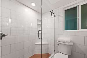 Bathroom with toilet, tile walls, and an enclosed shower