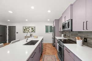 Kitchen featuring a kitchen breakfast bar, light parquet flooring, sink, gray cabinetry, and stainless steel appliances