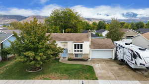 View of front of house featuring a mountain view, a front lawn, and a garage