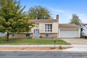 Raised ranch with a front lawn and a garage