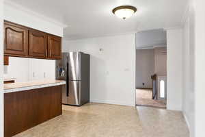 Kitchen with tile countertops, crown molding, and stainless steel fridge with ice dispenser