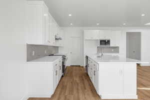 Kitchen featuring light wood-style floors, electric stove, built in microwave, under cabinet range hood, and a sink