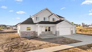 Modern farmhouse style home with a garage, stone siding, board and batten siding, and concrete driveway