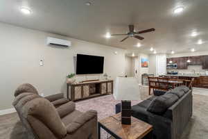 Living room featuring a wall mounted air conditioner, sink, light colored carpet, a textured ceiling, and ceiling fan