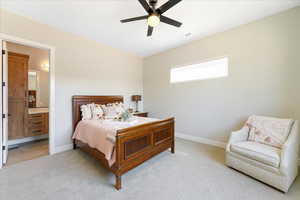 Bedroom featuring light carpet, ensuite bathroom, and ceiling fan