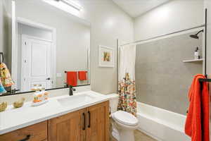 Full bathroom with toilet, shower / tub combo with curtain, vanity, and tile patterned floors