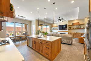 Kitchen featuring appliances with stainless steel finishes, a healthy amount of sunlight, a kitchen island with sink, and sink