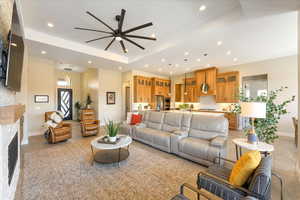 Living room featuring light hardwood / wood-style flooring, ceiling fan, and a raised ceiling