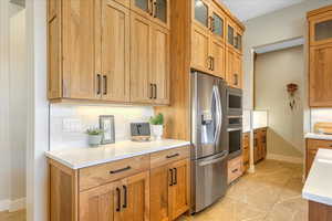 Kitchen featuring backsplash, appliances with stainless steel finishes, and light tile patterned floors