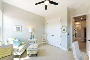 Living area with light colored carpet and ceiling fan