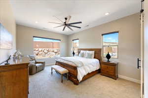 Bedroom featuring multiple windows, light colored carpet, and ceiling fan