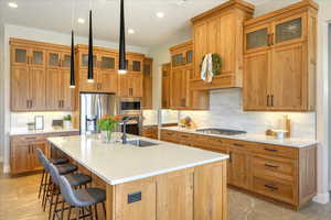 Kitchen with appliances with stainless steel finishes, a kitchen island with sink, sink, and a breakfast bar area