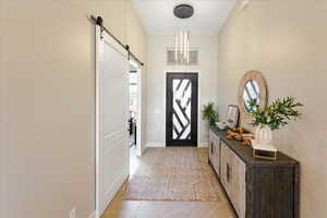 Tiled foyer entrance featuring an inviting chandelier and a barn door