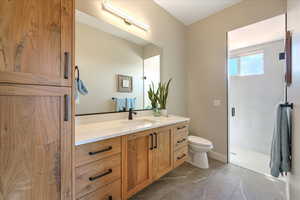 Bathroom with toilet, walk in shower, vanity, and tile patterned floors