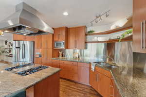 Kitchen featuring island exhaust hood, open shelves, stainless steel appliances, a sink, and light stone countertops